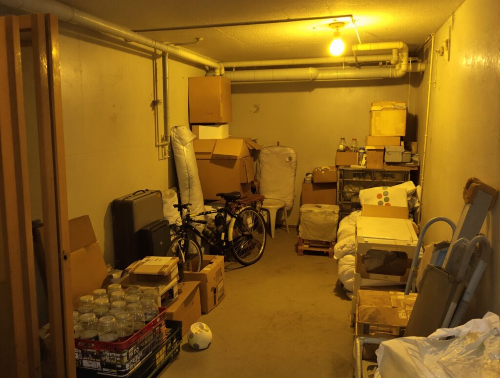 Cave d'immeuble à Vénissieux remplie de cartons, d'une valise et d'un vélo