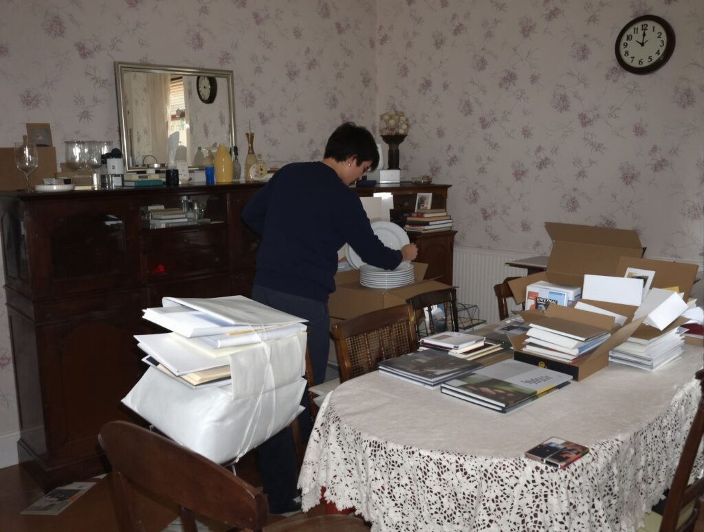 Intervenante qui emballe la vaisselle d'une salle à manger pendant un débarras de succession à Vénissieux